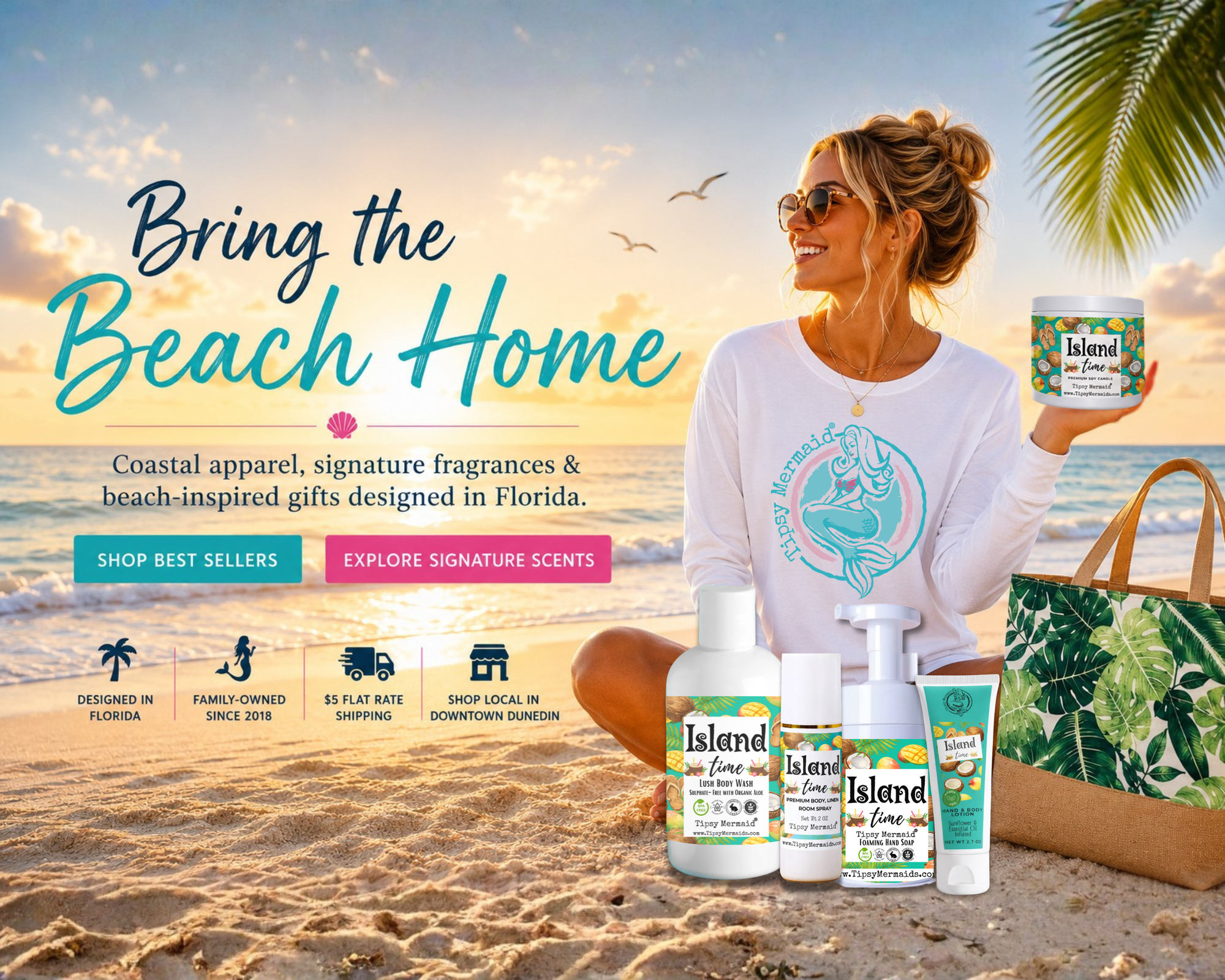 A woman sitting on a sandy beach holds a tin of Tipsy Mermaid Island Time Candle Coconut & Mango while surrounded by various scented products from Tipsy Mermaid, including body wash, lotion, soy candles and foaming hand soap. The scene is set against a tropical beach backdrop with palm trees and a sunset sky.